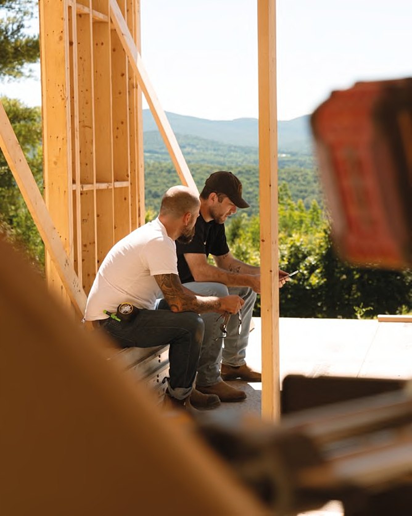 Two builders sitting in the framing, talking through the job